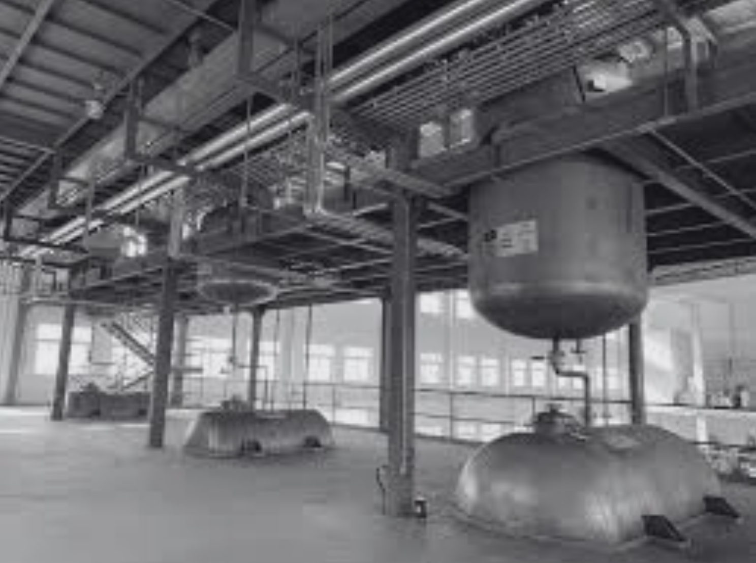 Industrial facility with large tanks, pipes, and structural metal framework.